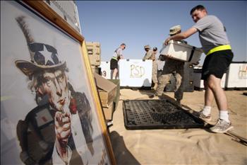 جنود من قوات الاحتلال الأميركي، وإلى جانبهم صورة «العم سام»، خلال نقلهم أعتدة عسكرية من قاعدة «فيكتوري» قرب بغداد إلى الولايات المتحدة أمس