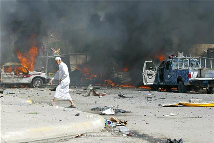 عراقي يسير قرب سيارات تحترق جراء تفجير انتحاري في كركوك امس (ا ف ب 