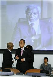 الامين العام للأمم المتحدة بان كي مون يتحدث إلى احد المندوبين، وتظهر في الخلف صورة كوفي انان على شاشة كبيرة، قبل بدء جلسة الجمعية العامة للأمم المتحدة امس. (أ ف ب) 
