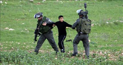 جنديان إسرائيليان يعتقلان طفلاً فلسطينياً خلال مواجهات قرب حاجز حوارة جنوب مدينة نابلس أمس (ا ب ا) 