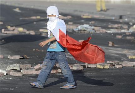 طفل ملثم وعلى أكتافه العلم البحريني يشارك في المواجهات مع قوات الأمن في قرية الدية في غربي المنامة أمس (ا ب ا) 