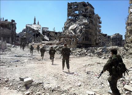جنود سوريون يتجولون في حي الخالدية في وسط مدينة حمص أمس بعدما أعلنت السلطات السورية السيطرة عليه أمس الأول (أ ف ب) 