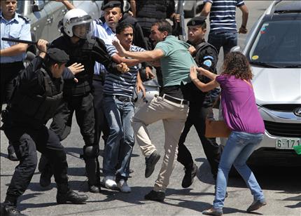 عناصر من الشرطة الفلسطينية يهاجمون متظاهرين خلال احتجاجات ضد العودة إلى المفاوضات في رام الله أمس (أ ف ب) 
