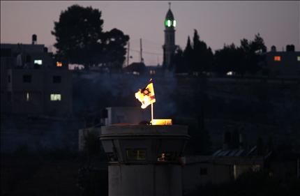 علم إسرائيلي يحترق فوق برج المراقبة في بلدة النبي صالح في الضفة الغربية أمس (أ ف ب) 