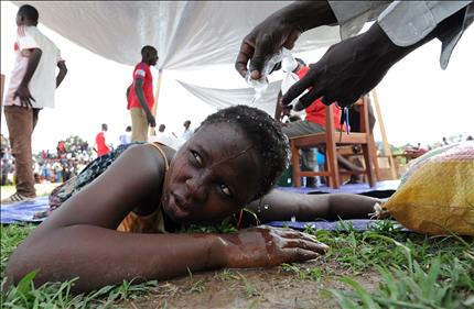 رجل يرش الماء على رأس امرأة حامل سقطت أرضاً أثناء توزيع المساعدات الغذائية في بانغي أمس (أ ف ب)