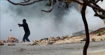 فلسطيني يرشق جنود الاحتلال الإسرائيلي بالحجارة في الضفة الغربية أمس (أ ب أ) 