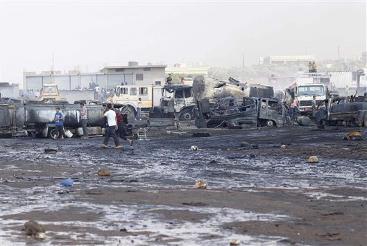 سوريون يتفقدون سوقا لبيع النفط بعد انفجار سيارة فيه في ريف ادلب امس (رويترز)