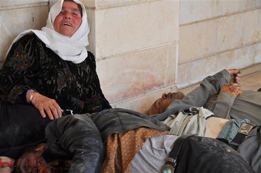 امرأة تنتحب الى جانب جثث رجال قتلهم عناصر "داعش" في قرية التليلية قرب بلدة رأس العين السورية الحدودية مع تركيا امس الاول (رويترز)