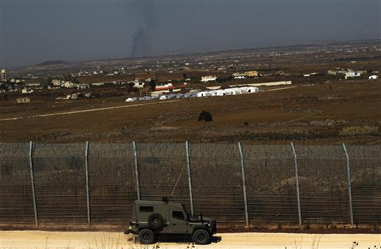 آلية عسكرية اسرائيلية في الجولان المحتل فيما يبدو مخيم للنازحين السوريين قرب قرية عيشة امس (ا ب ا)