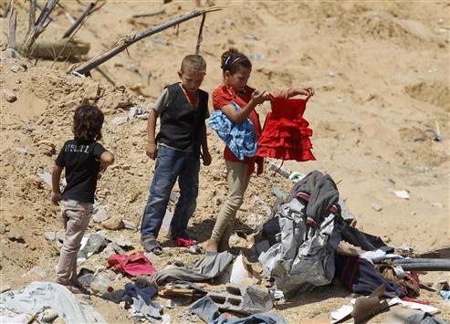 طفلة فلسطينية تحاول انقاذ ملابسها من بين ركام منزلها في خانيونس امس (ا ف ب)
