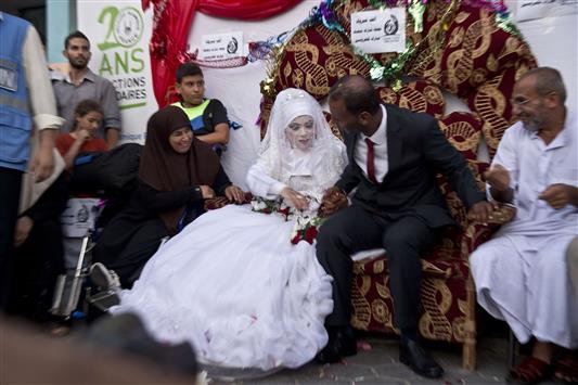 عروسان فلسطينيان خلال زفافهما في إحدى مدارس «الأونروا» في غزة أمس (أ ف ب)