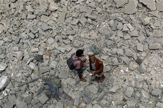 يمنيان يقفان وسط ركام مبانٍ دمرها قصف "التحالف" في صنعاء، أمس (أ ف ب)