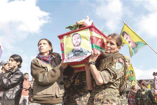 مقاتلات كرديات يحملن نعش الكندي جون غالاغر، الذي قتل خلال مشاركته في القتال الى جانب «وحدات حماية الشعب» في الحسكة، امس (رويترز)