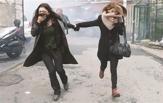 سيدتان تهربان بعد استخدام شرطة مكافحة الشغب للرصاص المطاطي عقب تظاهرة ضد اعتقال نواب من حزب «الشعوب الديموقراطي» في اسطنبول أمس الأول (أ ب أ)