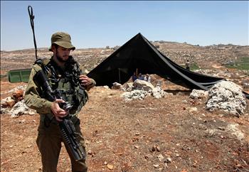 جندي من الاحتلال يحرس بؤرة استيطانية شرع المستوطنون في إقامتها في شرقي مدينة الخليل في الضفة الغربية أمس