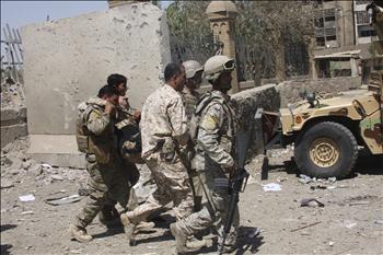 جنود عراقيون يساعدون زميلاً لهم أصيب في الهجوم الانتحاري في بغداد أمس