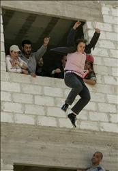 فتاة تقفز من مبنى خلال مناورة تدريبية للدفاع المدني السوري للتعامل مع الهزات الأرضية في دمشق أمس